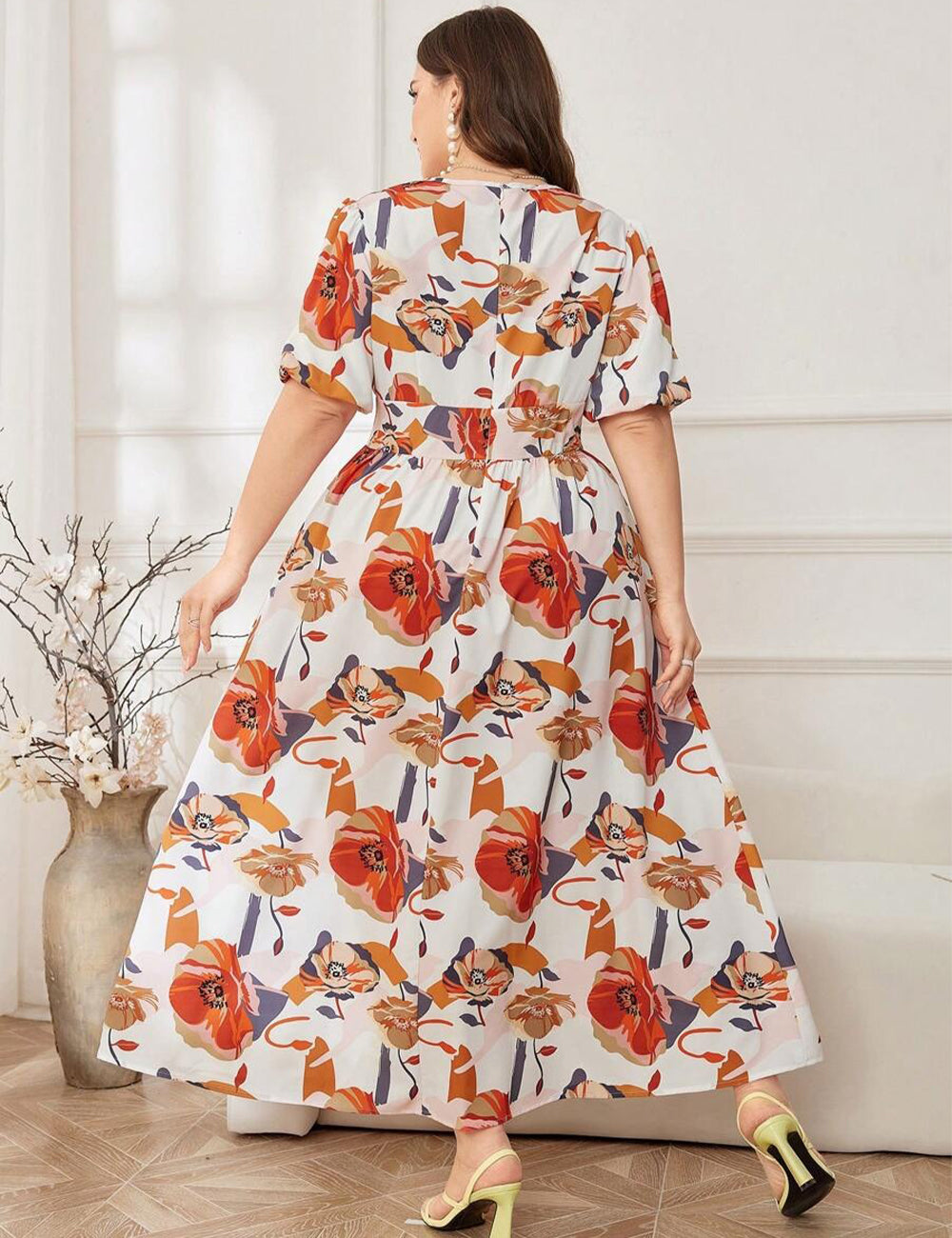 Woman wearing a floral dress in a room with a vase and plant.