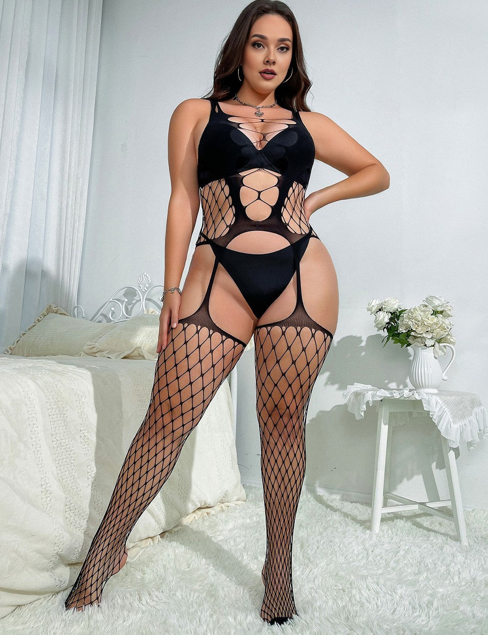 Woman wearing a black fishnet bodysuit in a bedroom setting