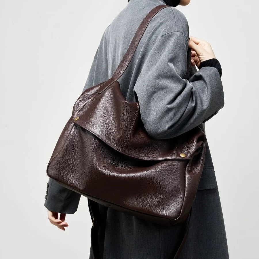 Person wearing a Coffee leather shoulder bag on a plain background