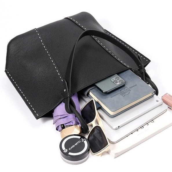 Black leather tote pouch with sunglasses, phone, and books