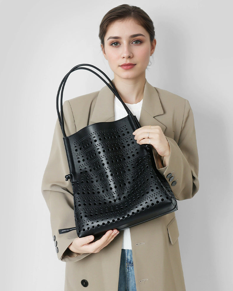 Woman holding a black perforated handbag