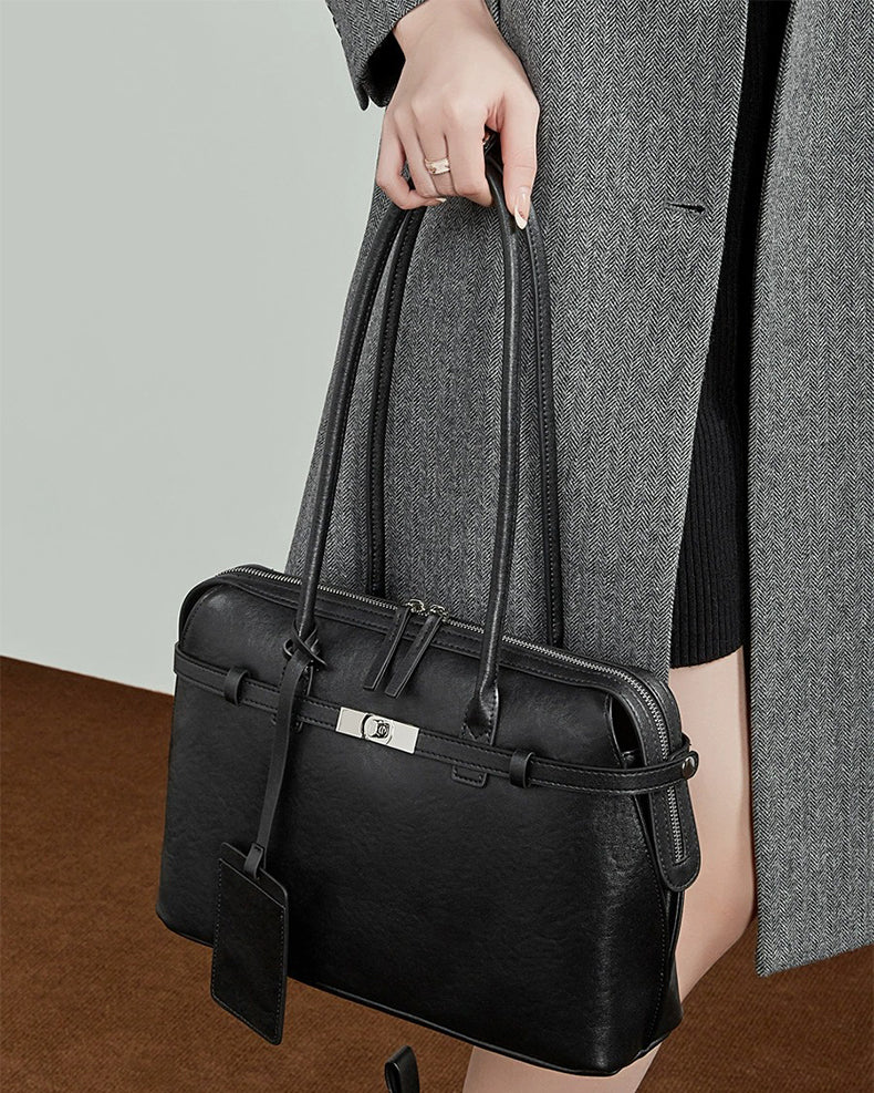 Person holding a black leather handbag