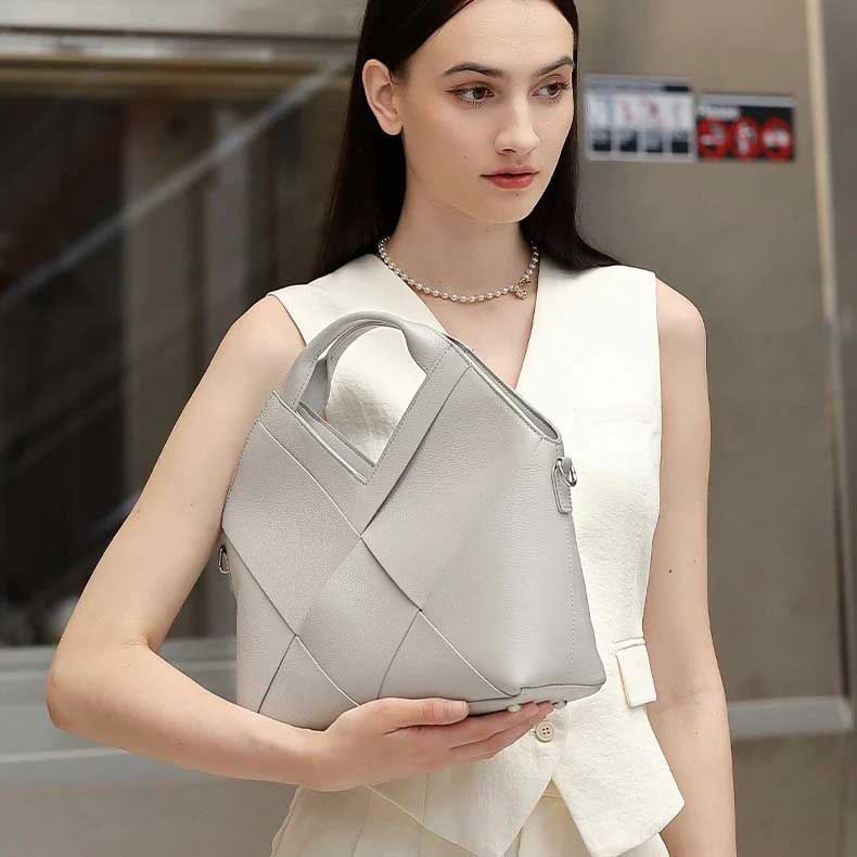 Woman holding a gray woven handbag