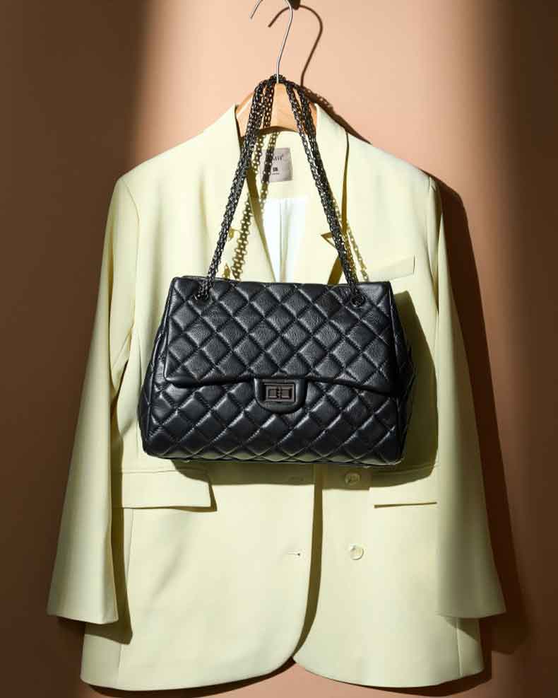 Black quilted handbag hanging on a beige blazer