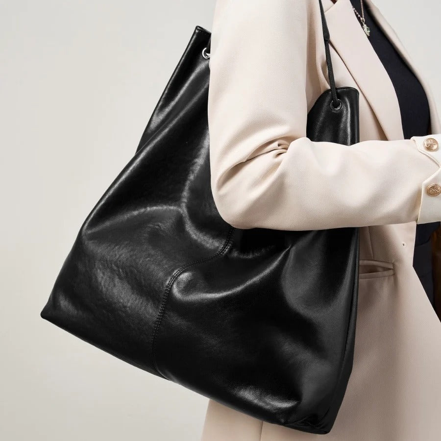 Person holding a black leather tote bag