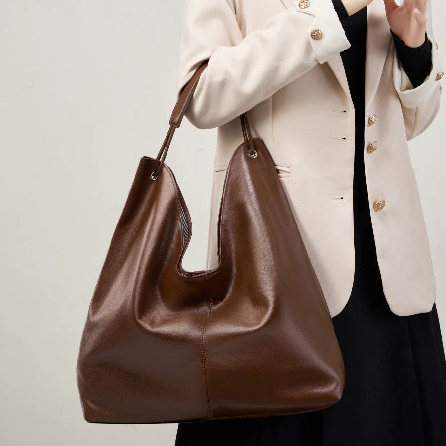 Brown leather handbag held by a person