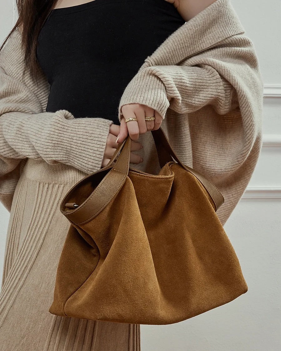 Person holding a brown suede handbag