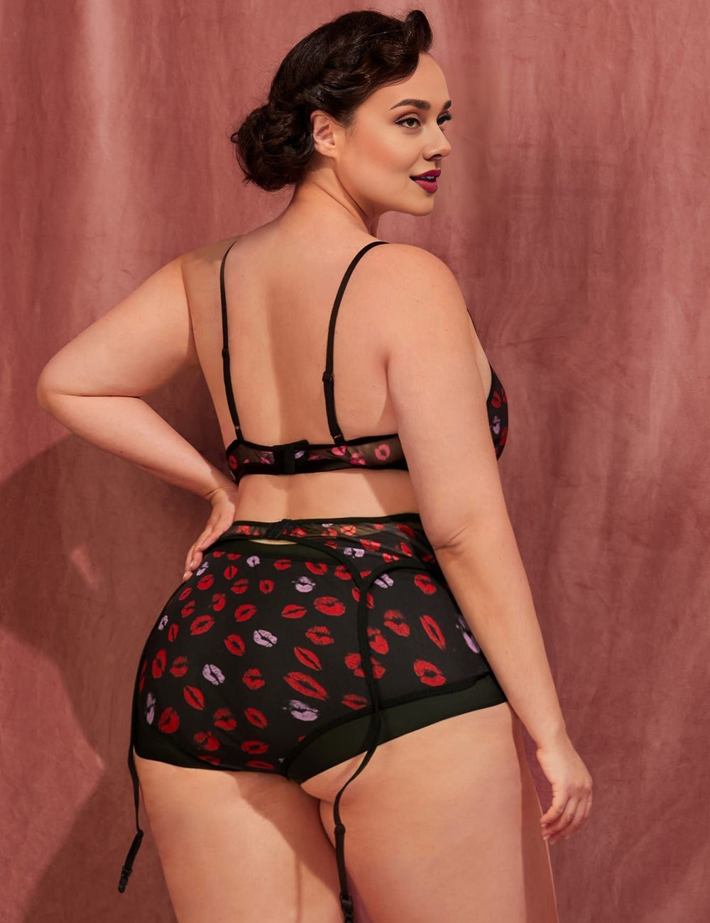 Women wearing a black lingerie set with red lip print against a pink background