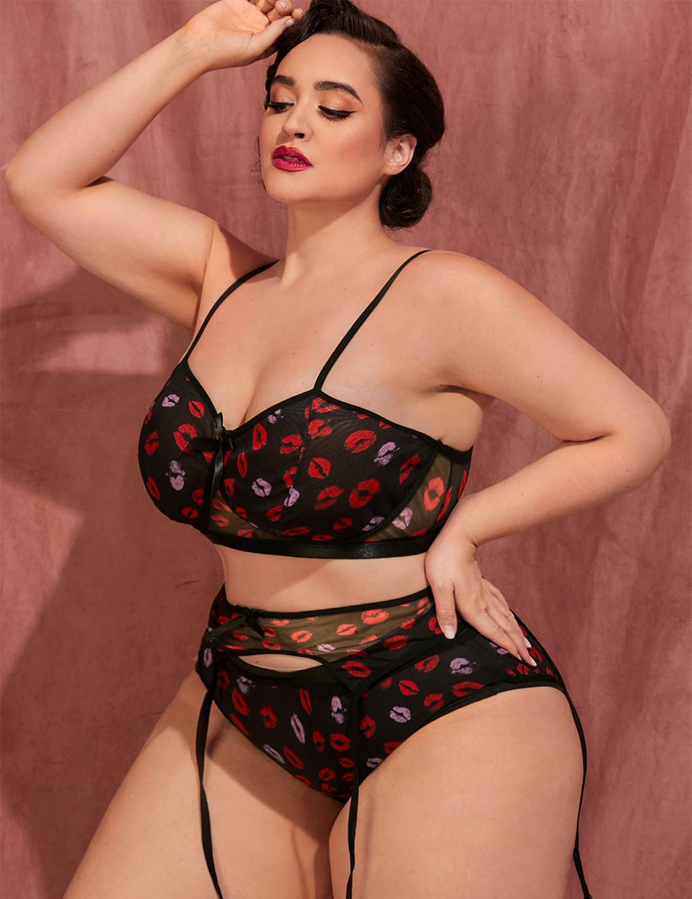 Women wearing a black lingerie set with red and purple accents against a pink background
