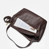 Coffee leather handbag with a strap on a white background