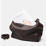 Coffee leather bag with a white card inside on a light gray background