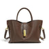 Coffee leather handbag with gold hardware on a white background