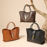 Three leather handbags in brown, black, and tan on a beige background with a branch.