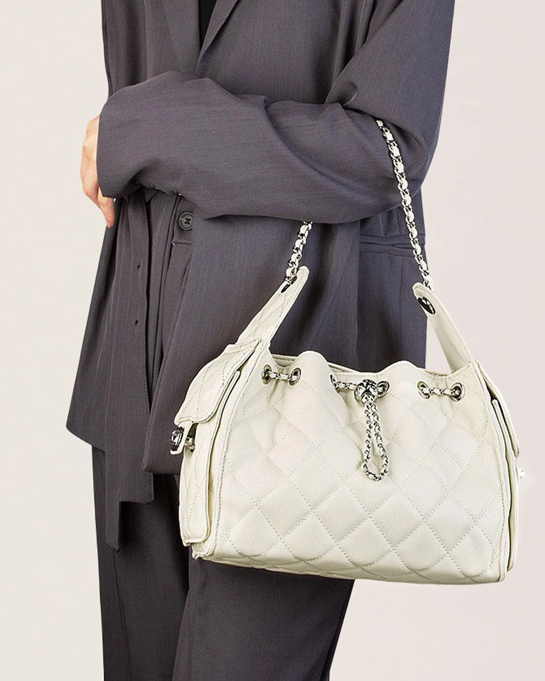 Person holding a off-white quilted handbag with a chain strap