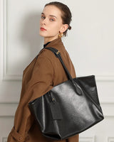 Woman carrying a black leather tote bag against a neutral background