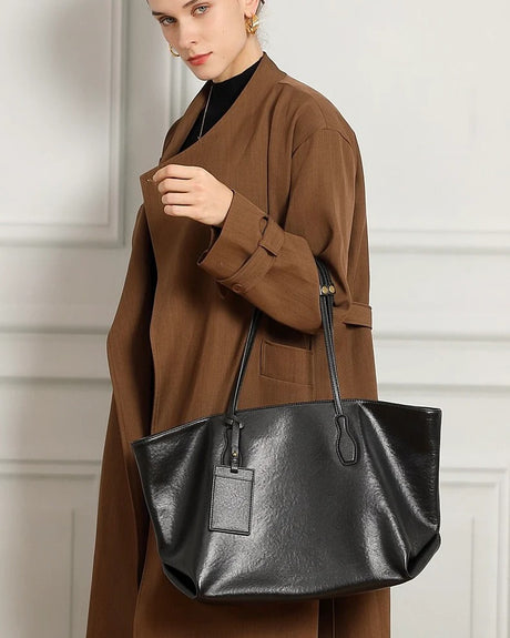 Person holding a black black Full Grain Leather handbag 