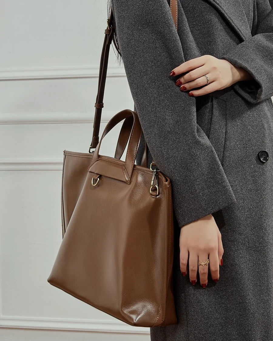 Person holding a brown leather handbag