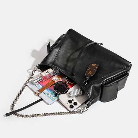 Black handbag with a chain strap containing various items 