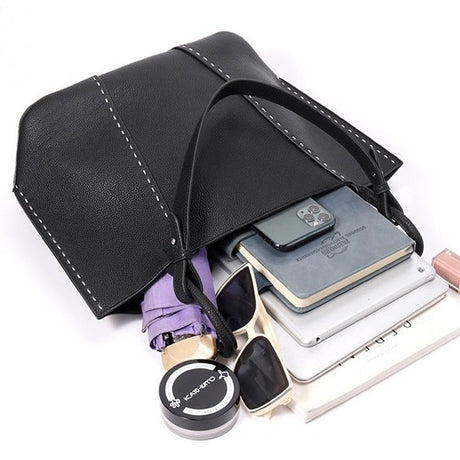 Black leather tote pouch with sunglasses, phone, and books 