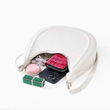 off-White handbag with its zipper open, revealing a pink heart-shaped pouch, black phone, and other items