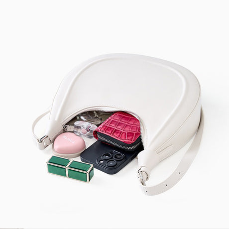 off-White handbag with its zipper open, revealing a pink heart-shaped pouch, black phone, and other items