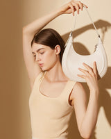 Woman holding a white Half Moon handbag 