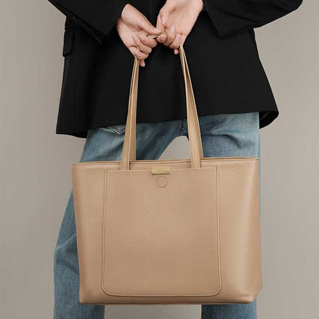 Person holding a beige tote bag