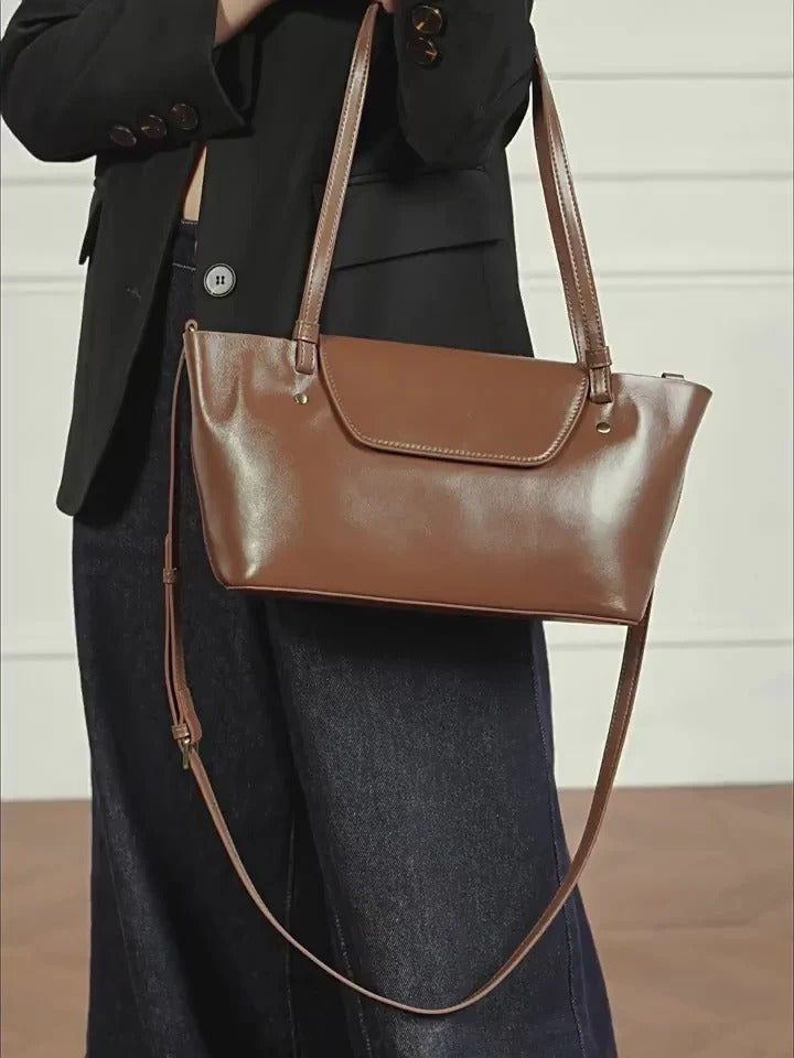 Brown leather handbag held by a person