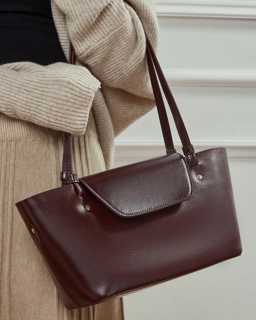 burgundy leather handbag held by a person 