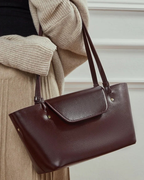 burgundy leather handbag held by a person 
