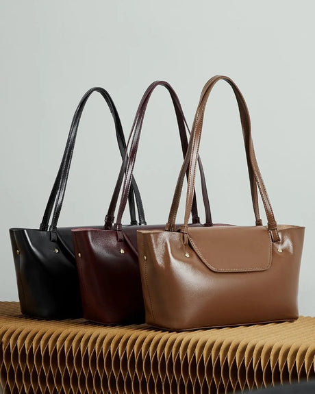 Three Genuine leather handbags in black, brown, and burgundy