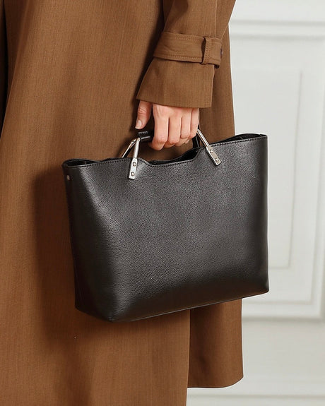 Person holding a black leather handbag 