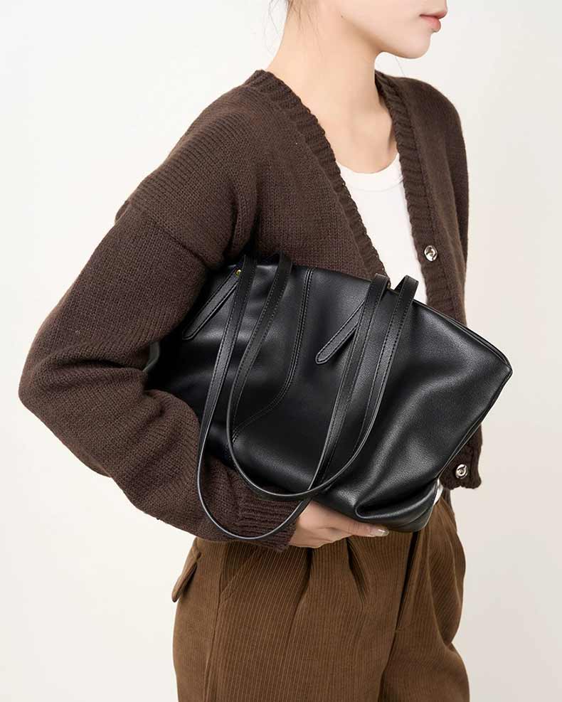 Person holding a black leather handbag 
