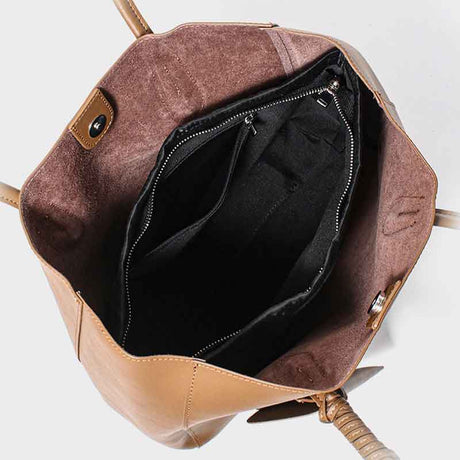 Brown leather bag with open top showing black interior 