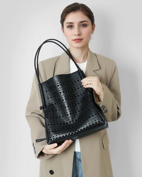 Woman holding a black perforated handbag 