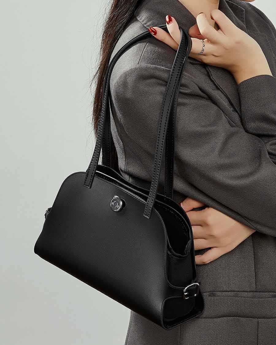 Person holding a black Genuine Leather handbag 