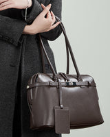 chocolate leather handbag with a tag held 