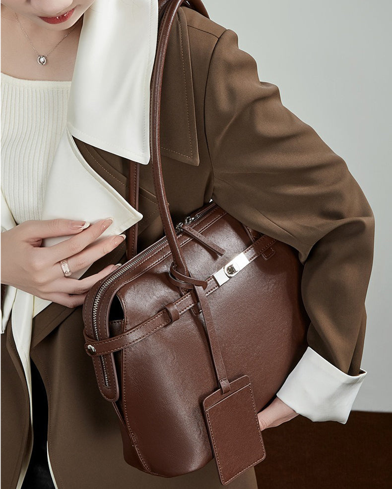 Person holding a brown leather bag 