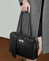 Person holding a black leather handbag 