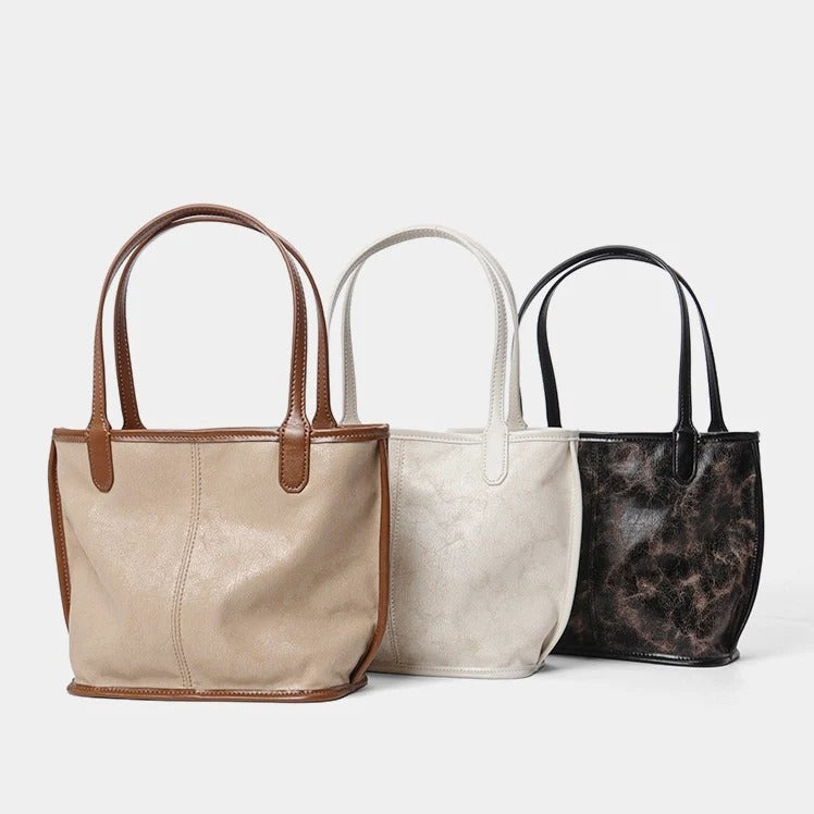 Three leather handbags in off-white, apricot, and black 