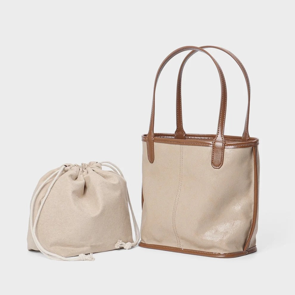 apricot Leather tote bag with brown handles and trim next to a beige drawstring bag 