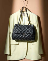 Black quilted handbag hanging on a beige blazer