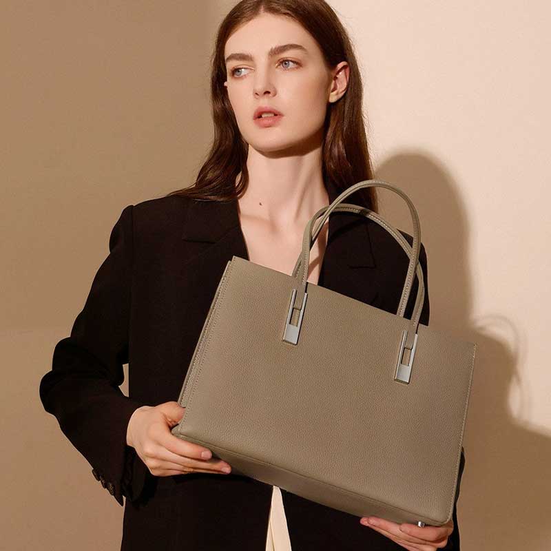 Woman holding a gray leather handbag 