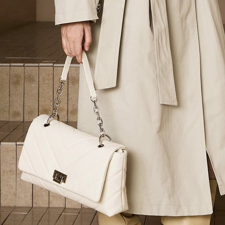 Person holding a white handbag with a chain detail