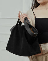 Person holding a black suede handbag 