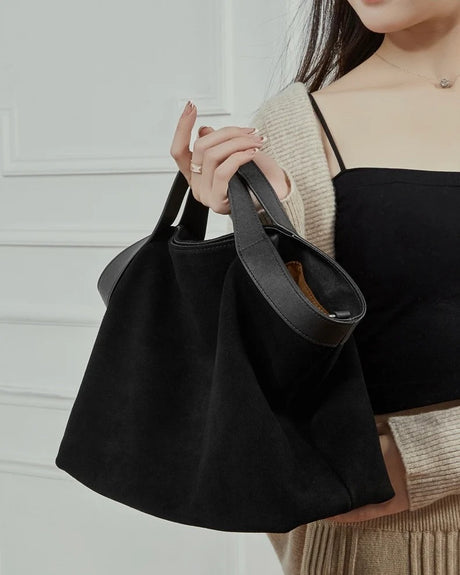 Person holding a black suede handbag 