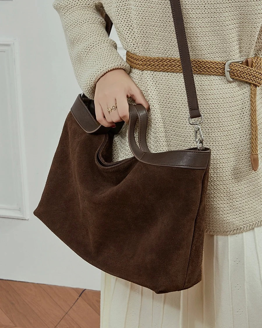 Person holding a brown leather handbag 