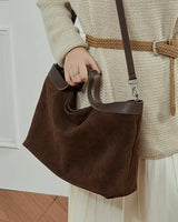 Person holding a brown leather handbag 