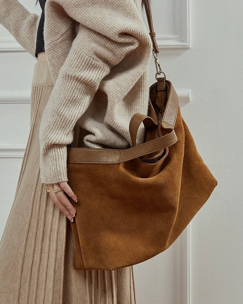 Person holding a brown suede handbag 