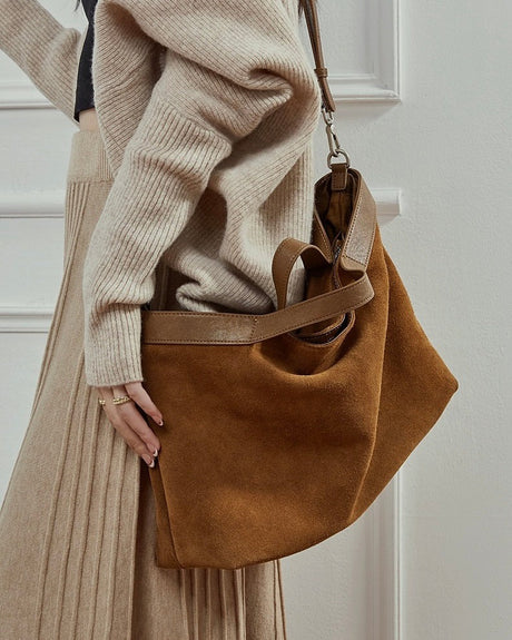 Person holding a brown suede handbag 